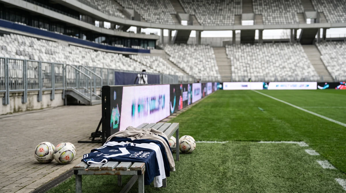 Pitchside LED advertising boards beside a football field before a match.